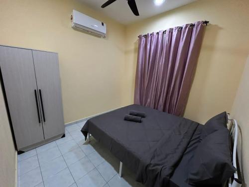 a bedroom with a bed and a purple curtain at Homestay D'Kampong in Teluk Intan
