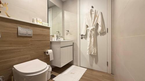 a bathroom with a toilet and a robe hanging on a door at Cozy Poolside 1BR - Serene Luxe Chic Retreat in Abu Dhabi