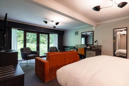 a bedroom with a bed and a desk and chairs at Mercure Newcastle George Washington Hotel Golf & Spa in Newcastle upon Tyne