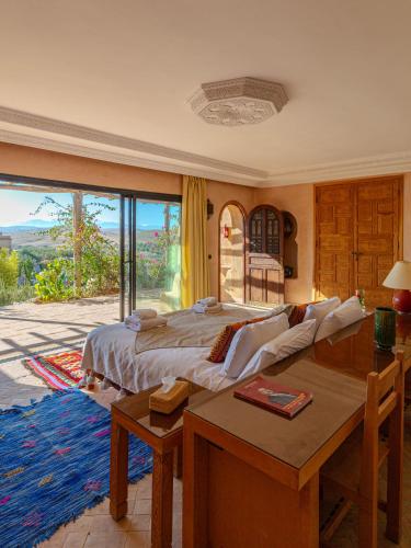 a bedroom with a bed and a table and a window at Les Jardins de la Santé in Tamazouzte