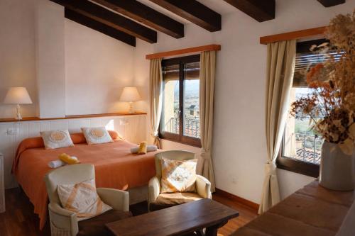 ein Schlafzimmer mit einem Bett, zwei Stühlen und einem Tisch in der Unterkunft Habitaciones con encanto - Cal Alejandro in Montsonis