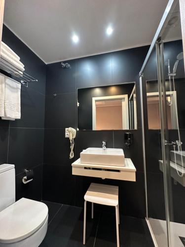 a bathroom with a sink and a toilet and a mirror at Hotel Pilar Plaza in Zaragoza