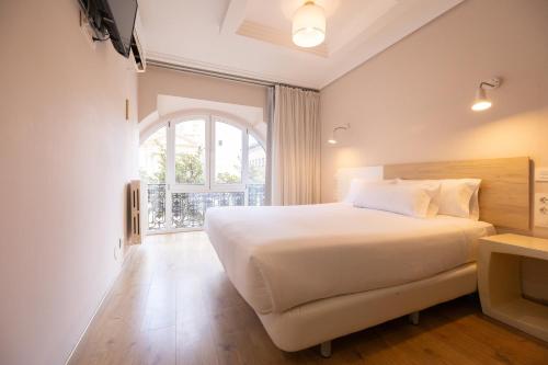 a bedroom with a large white bed and a window at Hotel Pilar Plaza in Zaragoza