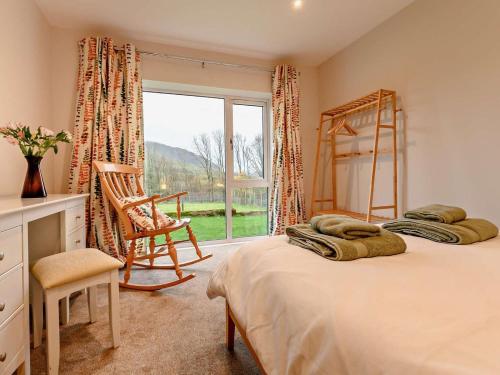 a bedroom with two beds and a chair and a window at 3 Bed in Keswick oc-93589 in Threlkeld