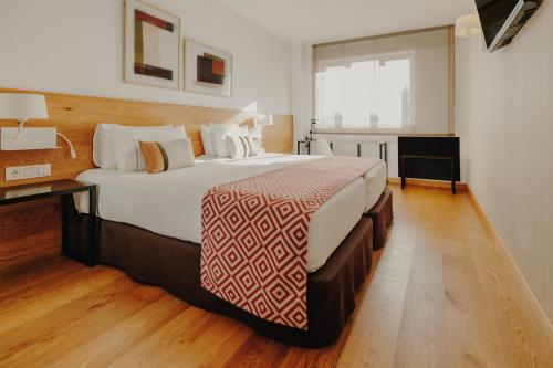 a bedroom with a large bed and a desk at Rafaelhoteles Atocha in Madrid