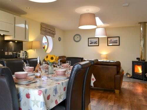 a dining room with a table with plates and chairs at Porthole Cottage in Allonby
