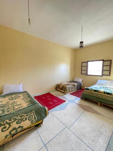 a room with two beds and rugs on the floor at Sahara desert Maison in Merzouga