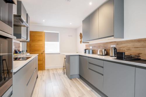 a kitchen with gray cabinets and a wooden floor at Charlotte Cottage - Minutes from Poole Park, with Feature Log Burner in Poole