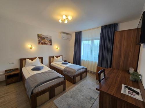 a hotel room with two beds and a desk at Pensiunea Transilvania in Sibiu
