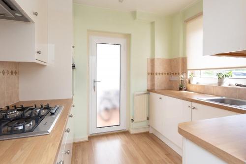a kitchen with white cabinets and a door with a window at Harry Potter Studios Bungalow and Private Garden with Parking in Watford