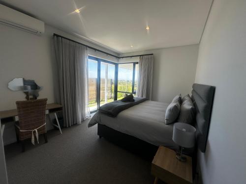 a bedroom with a bed and a large window at Seabreeze Golf Retreat in St Francis Bay