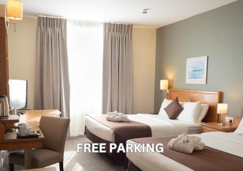 a hotel room with two beds and a desk at Future Inn Cardiff Bay in Cardiff