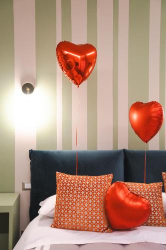 two red heart balloons are hanging above a bed at Numero 5 B&B in Francavilla al Mare