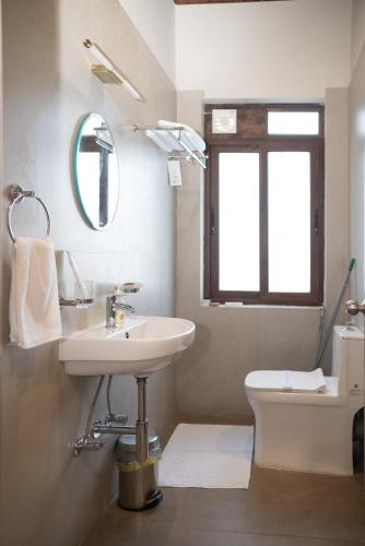a bathroom with a sink and a toilet and a mirror at Ara Ki Serviced Apartments in Kohīma