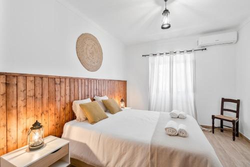 a bedroom with a large white bed with towels on it at Casa da Ritinha - Praia Azenhas D El Rey in Montes Juntos