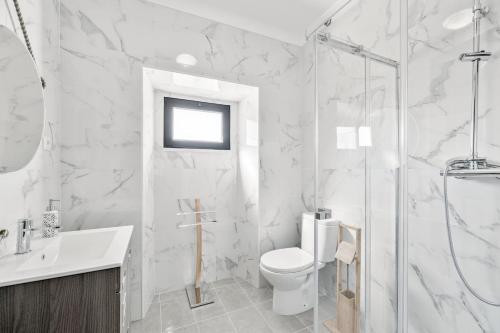 a white bathroom with a toilet and a shower at Casa da Ritinha - Praia Azenhas D El Rey in Montes Juntos