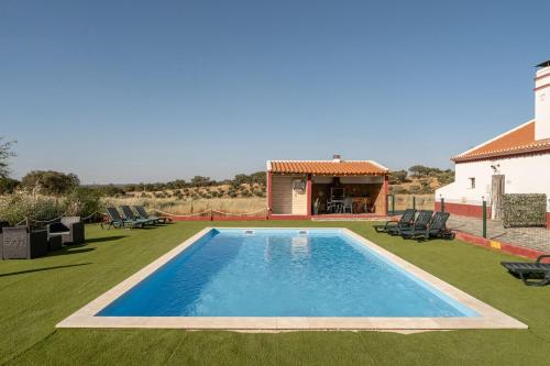 a swimming pool in a yard with chairs and a house at Casa da Ritinha - Praia Azenhas D El Rey in Montes Juntos