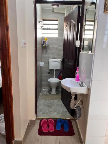 a bathroom with a sink and a toilet with two flip flops at Serenity Homes in Ruiru