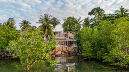 a house in the middle of a river with trees at Villa Amrita - Oceanfront Villa with Private Beach in Ko Phangan