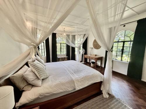 a bedroom with a canopy bed with white curtains at Hornbill Cottage in Nairobi