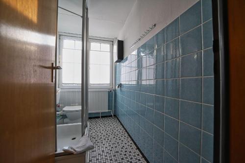 a bathroom with a toilet and a blue tiled wall at Appartement-8 in Süddorf