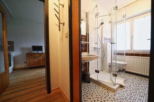 a bathroom with a glass shower and a sink at Appartement-3 in Süddorf