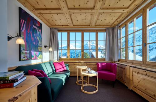 un soggiorno con un divano verde e sedie rosa di Hotel Stoffel - adults only a Arosa