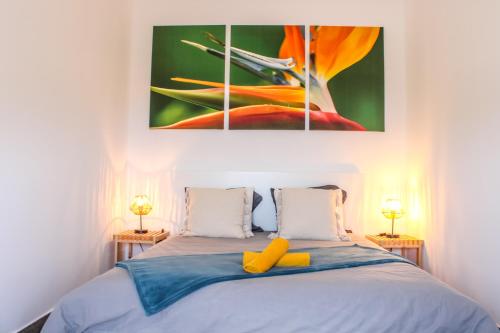 a bedroom with a bed with a painting on the wall at Casa da Vila Apartments in Arco da Calheta