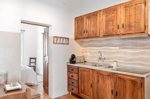 a kitchen with wooden cabinets and a sink at Casa da Ti Inácia - Praia Azenhas D El Rey in Montes Juntos