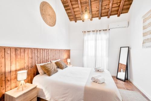 a bedroom with a large white bed with towels on it at Casa da Ti Inácia - Praia Azenhas D El Rey in Montes Juntos