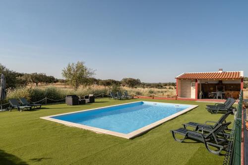 a swimming pool with two chairs and a house at Casa da Ti Inácia - Praia Azenhas D El Rey in Montes Juntos