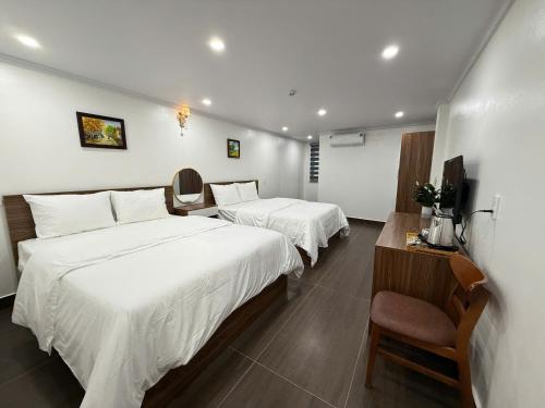 a hotel room with two beds and a chair at Galaxy Airport Hotel in Hanoi