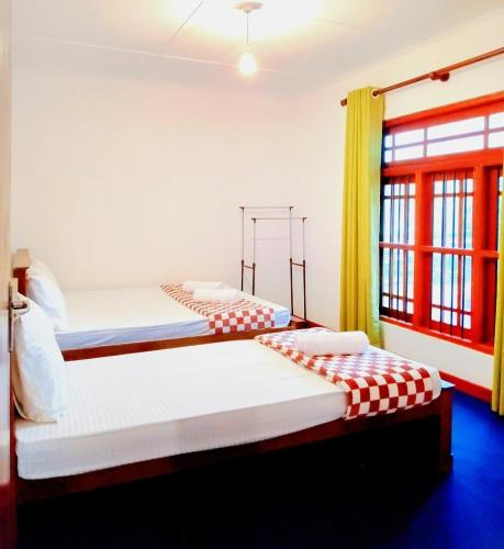 two beds in a room with a window at Ceyonra Evermist Residence in Nuwara Eliya