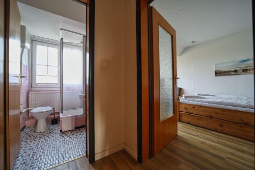 a bedroom with a bed and a bathroom with a toilet at Appartement-6 in Süddorf