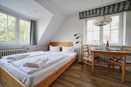 a bedroom with a bed and a desk and windows at Appartement-7 in Süddorf