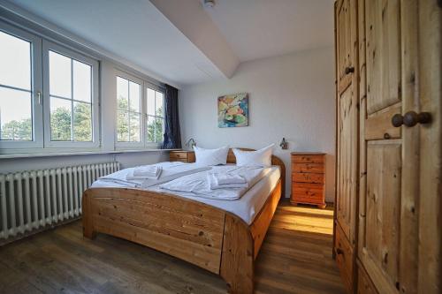 a bedroom with a wooden bed and two windows at Appartement-5 in Süddorf