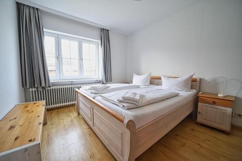 a bedroom with a bed with white sheets and a window at Appartement-9 in Süddorf