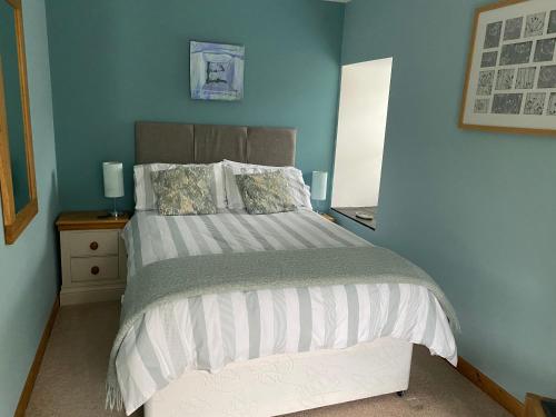 a bedroom with a bed with a blue wall at Garth Engan B&B with private lounge in Llanbedr