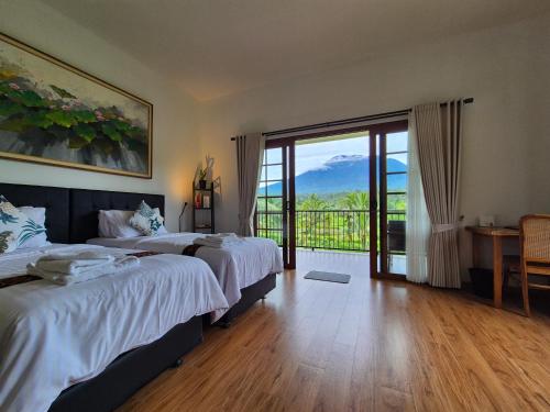 a hotel room with two beds and a balcony at A Calm Spacious Cottage with Mount Agung View in Selat