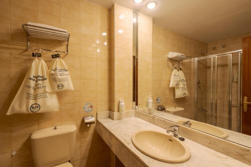 ein Badezimmer mit Waschbecken, Toilette und Spiegel in der Unterkunft B&B HOTEL Gijón Centro Begoña in Gijón