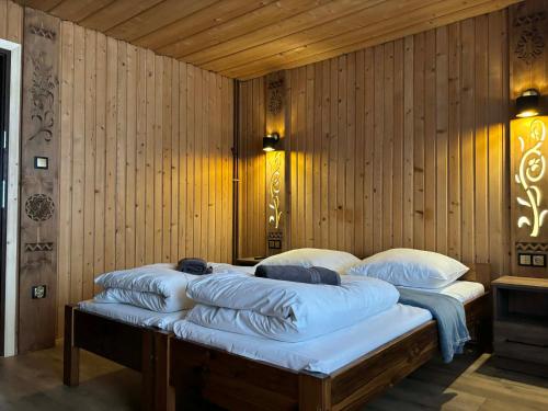 two beds in a room with wooden walls at Felągówka in Murzasichle