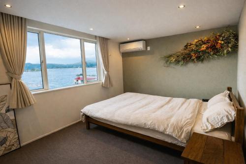 a bedroom with a bed with a view of the water at The Lake House 野尻湖 in Shinano