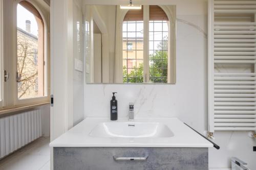 a white bathroom with a sink and a mirror at A Casa Gualandi in Bologna