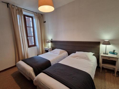 a hotel room with two beds and a window at Le Relais Des Dix Crus - Logis Hôtel in Corcelles-en-Beaujolais