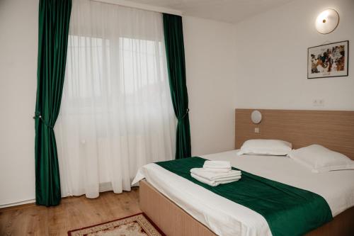 a bedroom with a bed with green and white sheets at Motel Moara Veche in Săcălăşeni