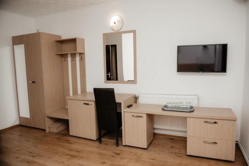 a room with a desk and a television on a wall at Motel Moara Veche in Săcălăşeni