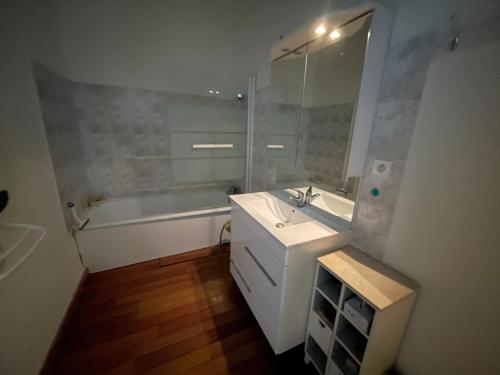a bathroom with a sink and a tub and a mirror at Grande Chambre avec parking possible en supplément, BORDEAUX BASTIDE in Bordeaux
