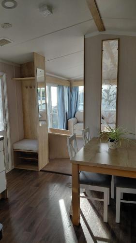 a living room with a wooden table and a dining room at Driftwood at Freshwater Beach Holiday Park in Burton Bradstock