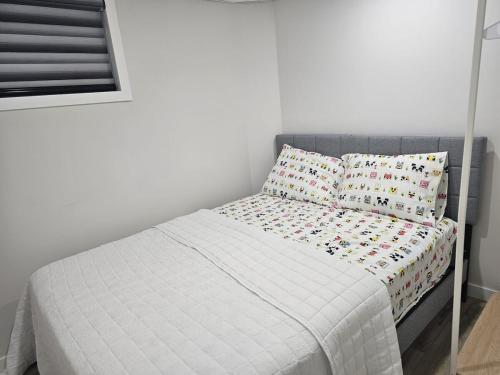 a small bed with a white bedspread and two pillows at 2 Bedroom Suite in Transcona in Winnipeg
