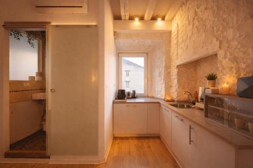 a kitchen with white cabinets and a stone wall at Little Urban Home in Trieste